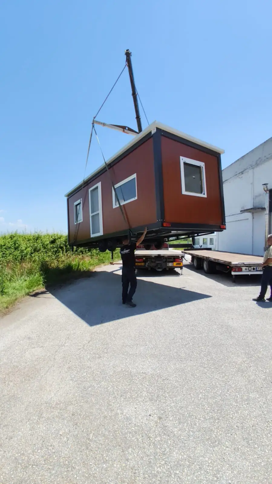 Crane lifting a small cabin under a blue sky