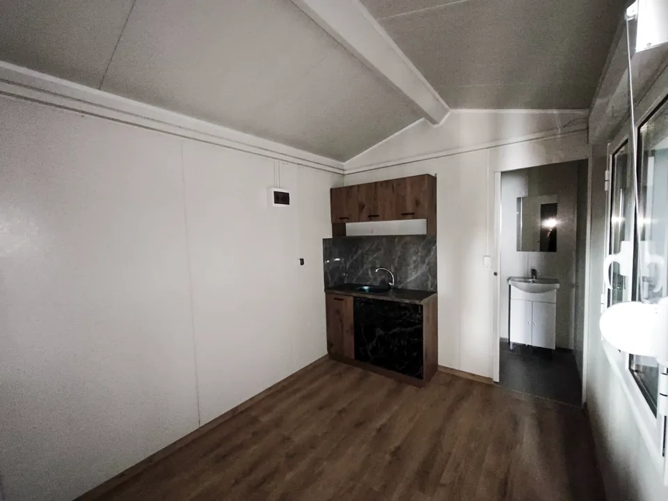 Open-plan interior with timber floor, the kitchen at the back and the bathroom on the right