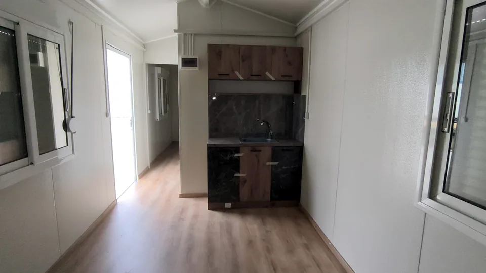 Room with the kitchen at the far end and windows on both sides