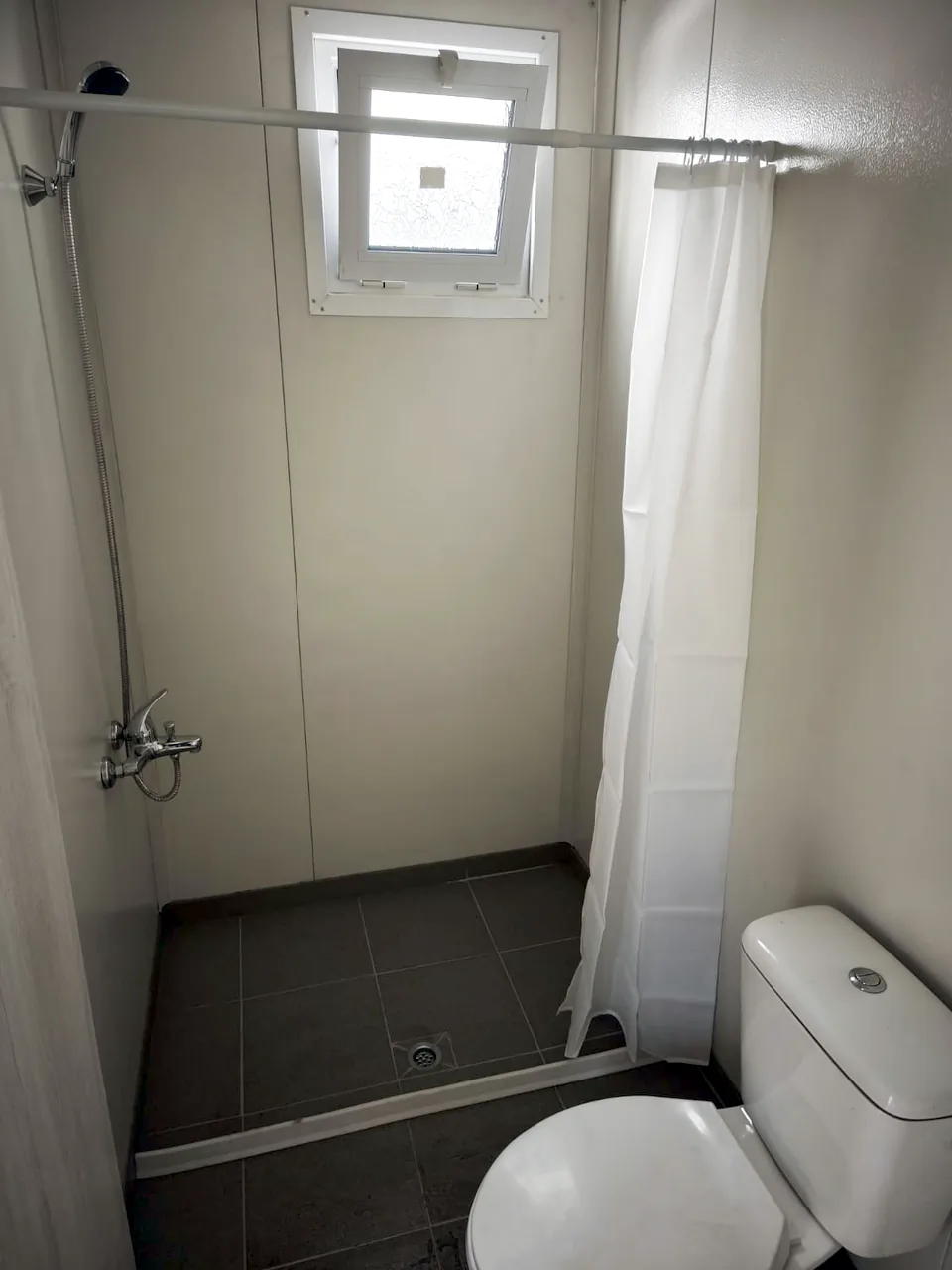 Mobile home bathroom with shower, toilet and a small window